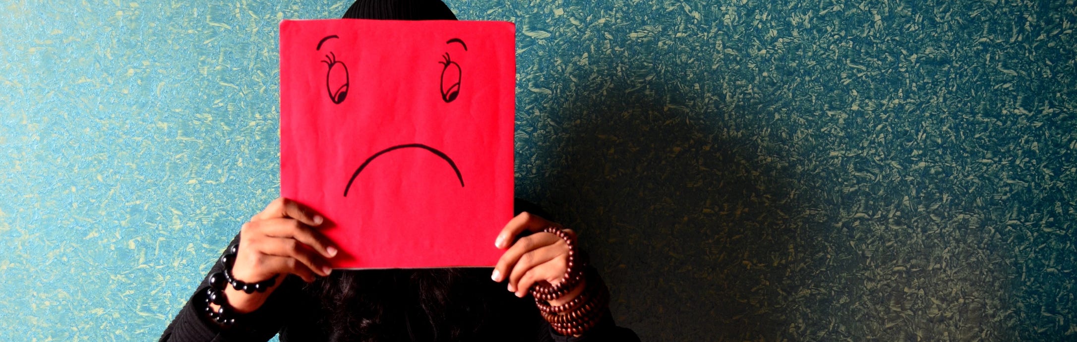 A Depressed Woman covering her face with a sign